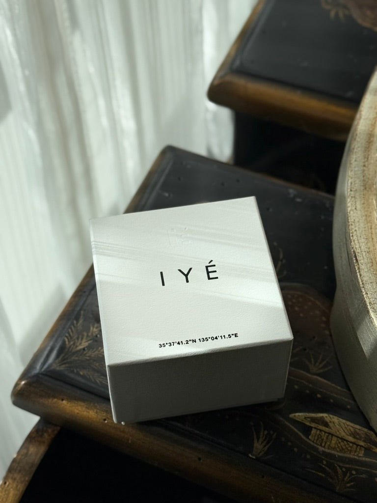 IYé product packaging on a wooden surface with a white curtain background