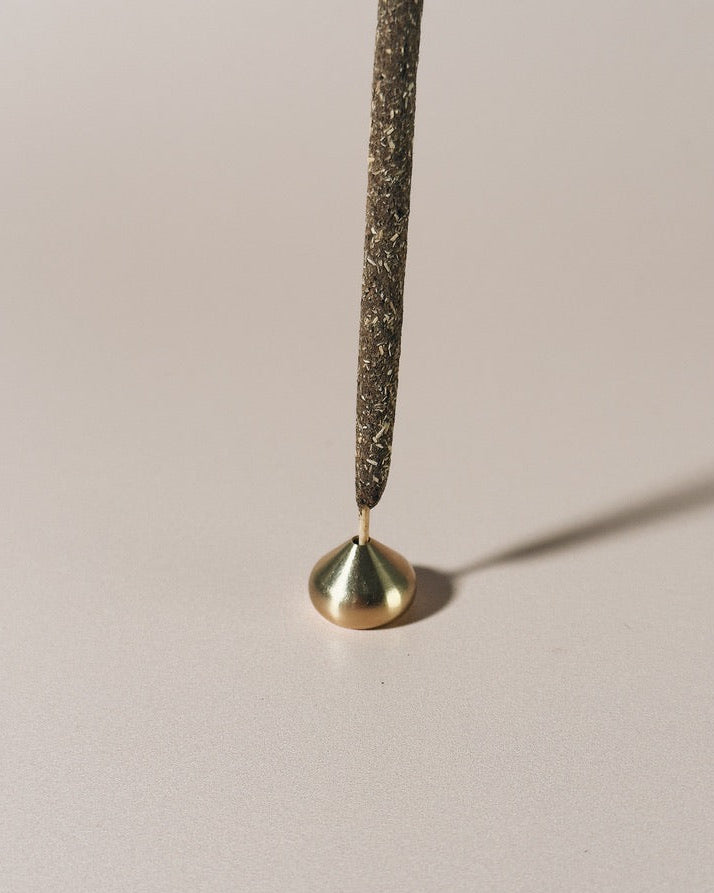 Medium brass waterdrop incense holder holding a bamboo core incense stick, photographed against a light background.