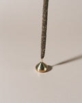 Medium brass waterdrop incense holder holding a bamboo core incense stick, photographed against a light background.
