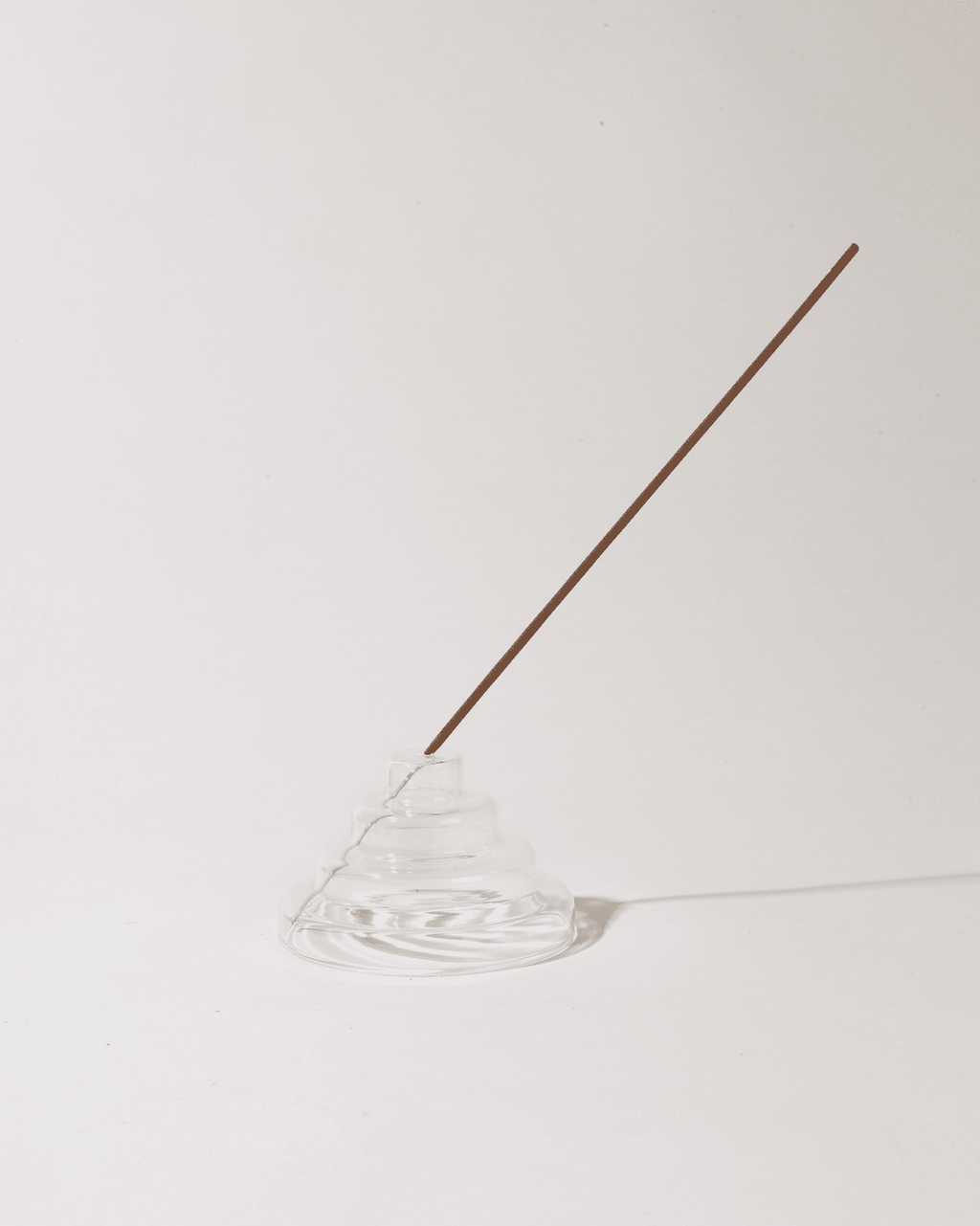 clear meso incense holder containing incense on a neutral white background