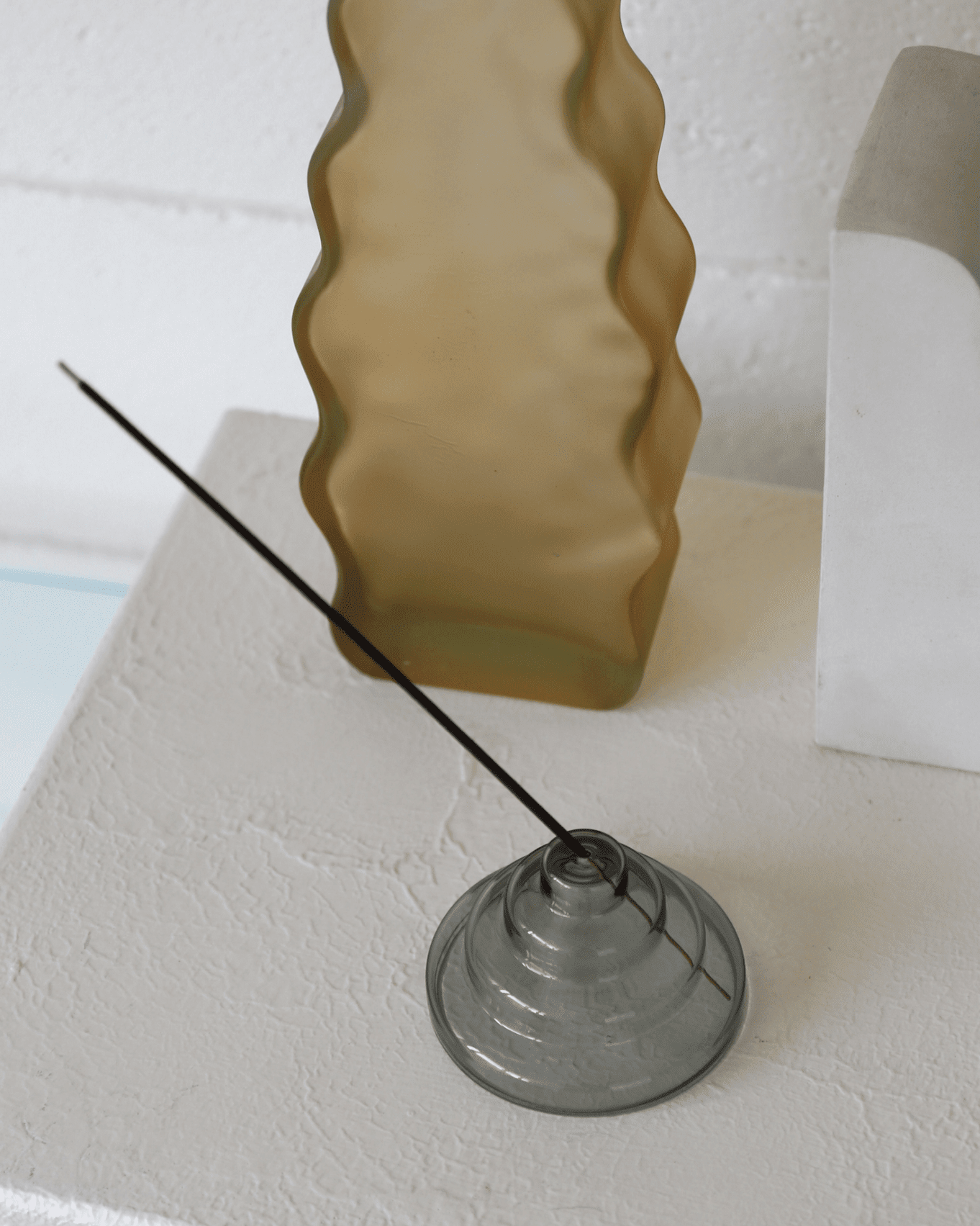 gray meso holder on cement surface holding incense stick