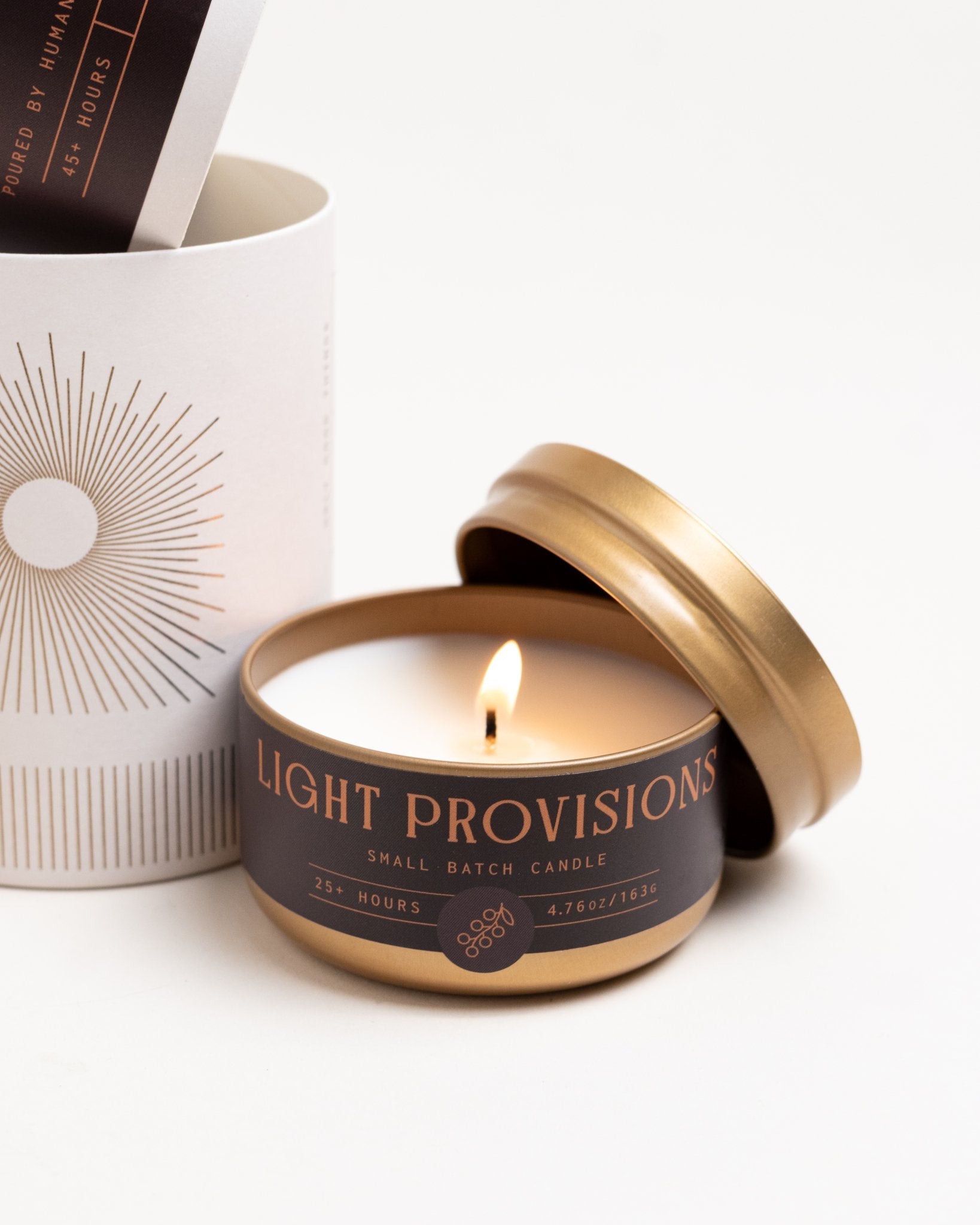 Oak and Currant travel tin candle burning with gold lid off on white background