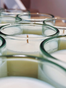 Batch of Gypsophila candles in bright aqua recycled glass, showcasing hand-poured wax and circular glass rims in studio lighting.