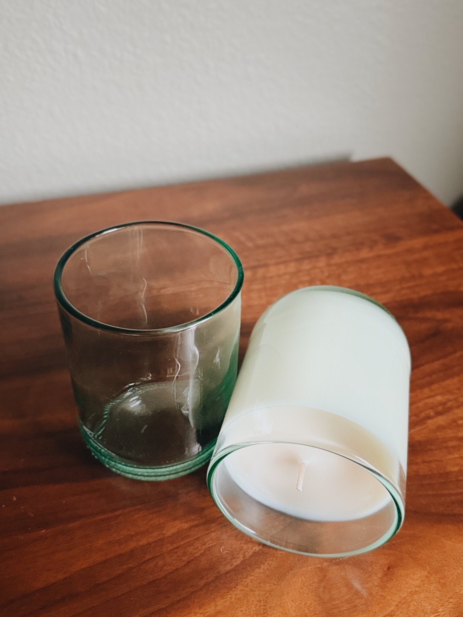Two glass recycled aqua candle holders on a wooden surface with a white background