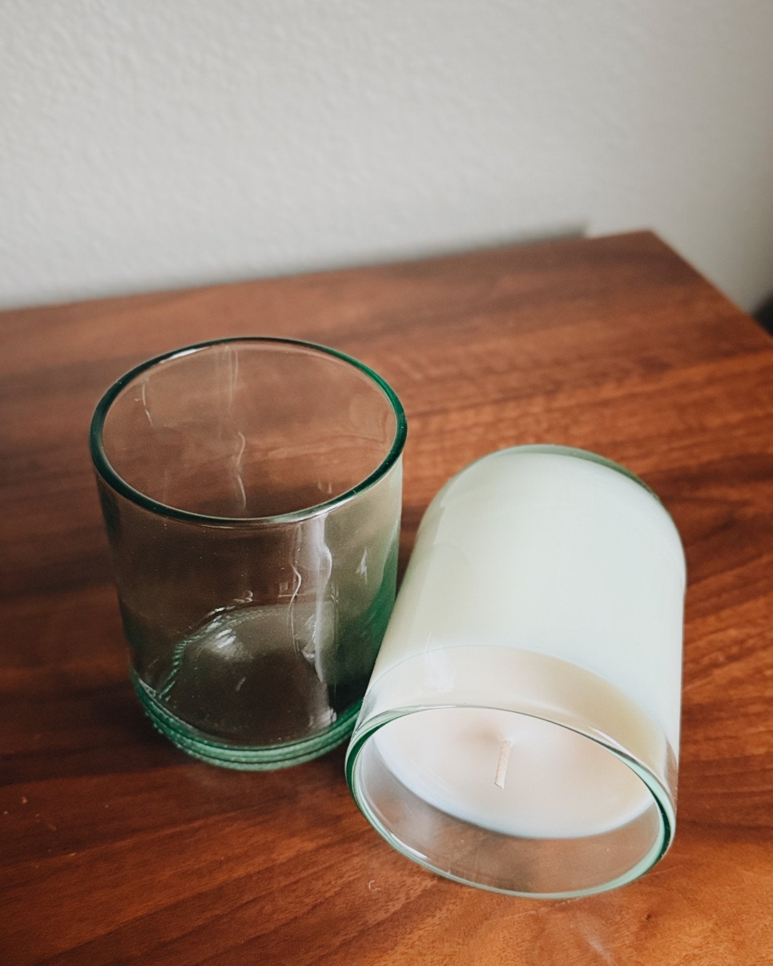 Two glass recycled aqua candle holders on a wooden surface with a white background