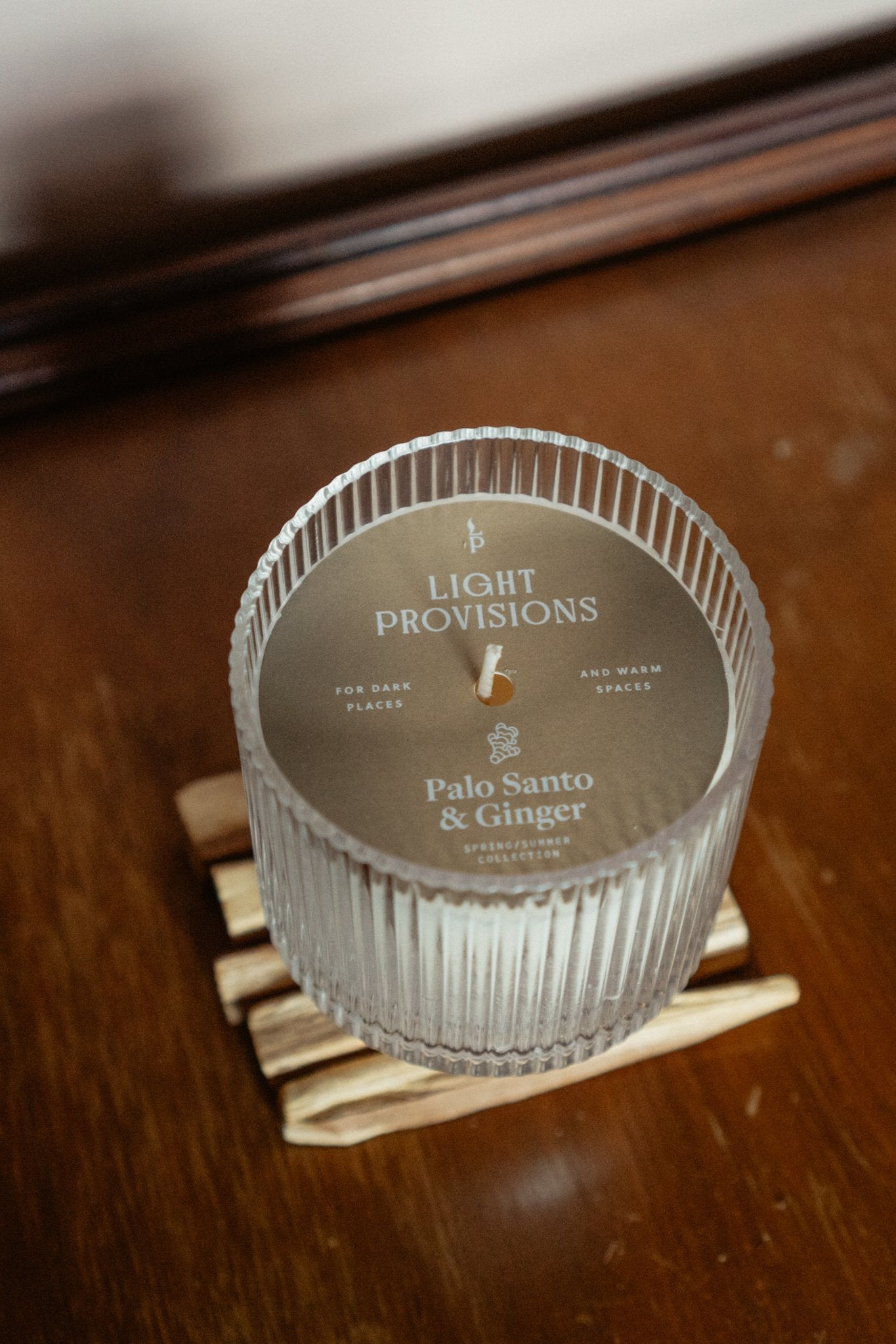 Top view of Palo Santo Ginger Candle in ribbed glass tumbler with palo santo sticks on wooden surface