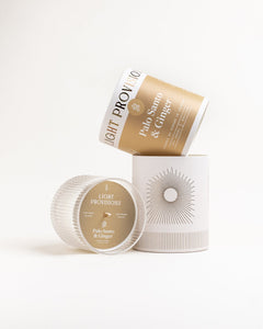 Palo Santo & Ginger display with tilted tumbler box and paper tube next to ribbed glass lid, on white background.
