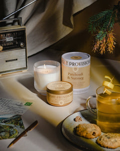 Light Provisions Patchouli & Nutmeg lit candles with travel tin, tea, cookies, pine branch and vintage camera styling
