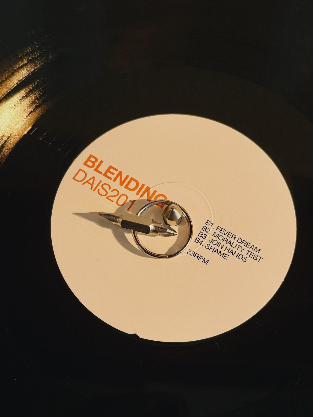 Pocket maintenance screwdriver resting on a vinyl record