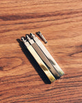 Three Tsubota Pearl Queue lighters in gold, silver, and black next to flint assembly replacement part