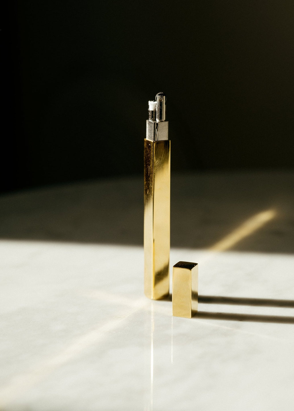 Slim Queue stick lighters in gold finish standing upright on a neutral surface