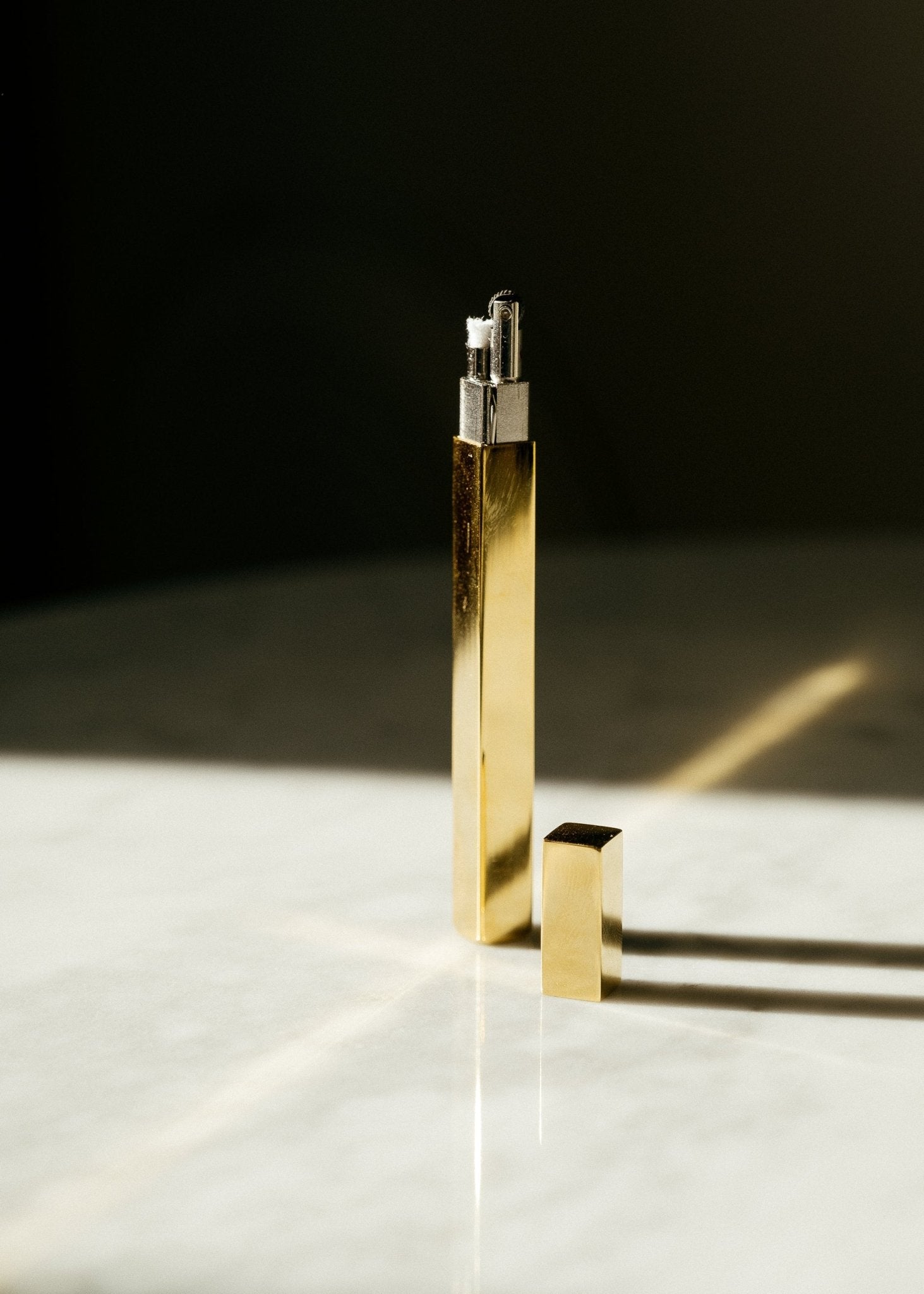 Slim Queue stick lighters in gold finish standing upright on a neutral surface