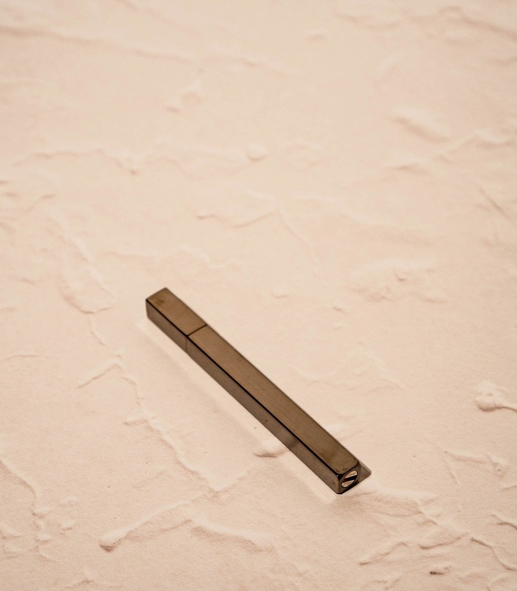 Black / Slate Queue Lighter by Tsubota Pearl laying flat on textured beige surface