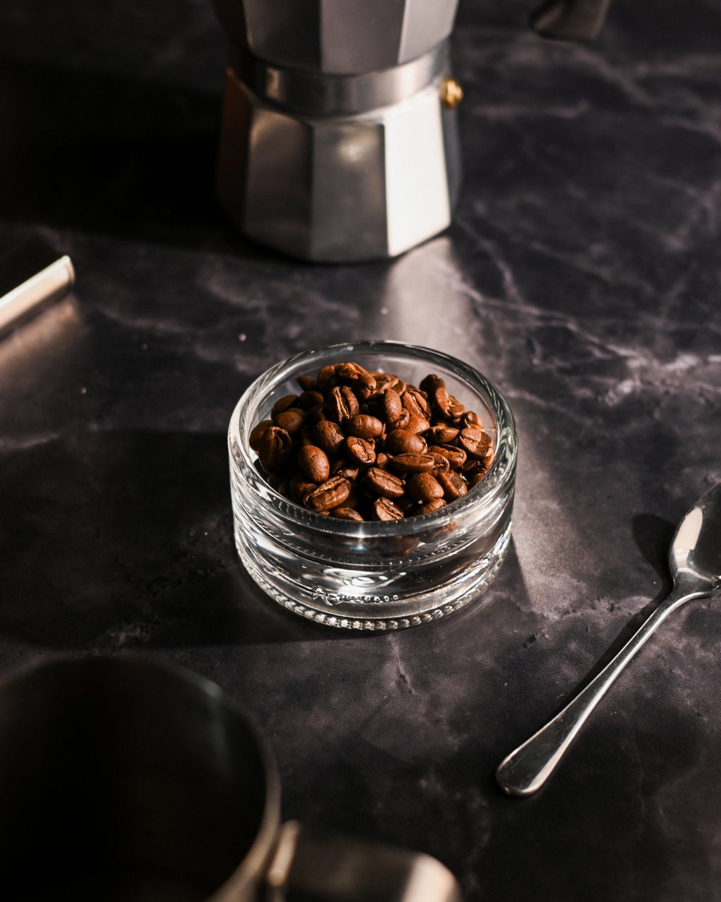 Clear reclaimed bottle glass dish used for coffee beans on a kitchen counter