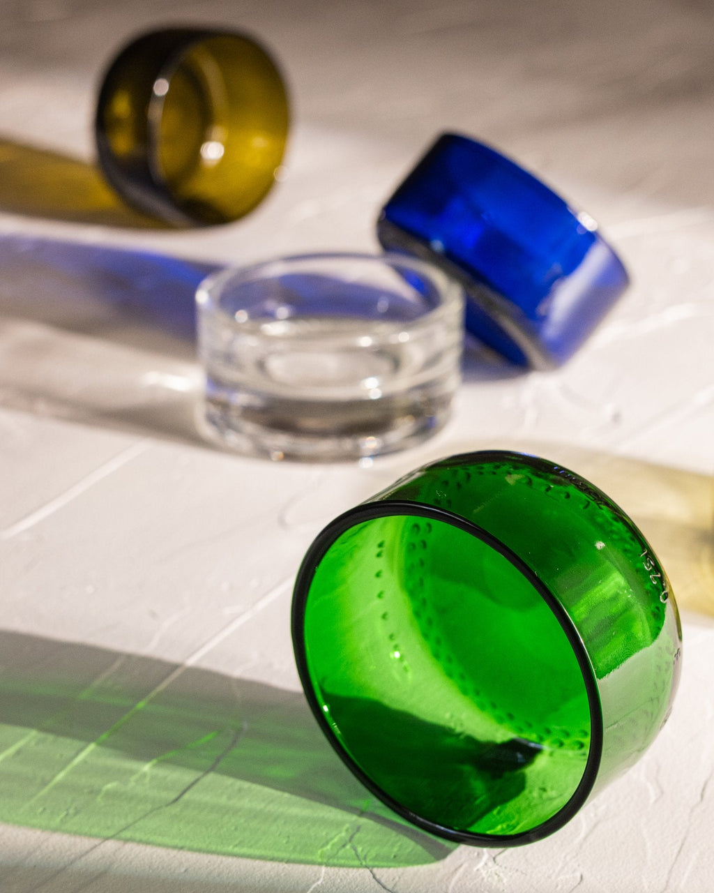 Reclaimed bottle glass dishes in blue, green, amber, olive, and clear, with green in the focal point