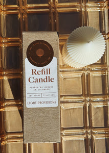 Dry Leaves & Cardamom Refill candle packaging with a candle on a textured gold surface