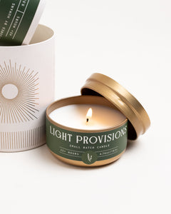 Close-up of lit Rosemary & Cedar travel tin showing smooth wax and centered flame, on white background.