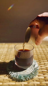 POV: pouring cream into signature ripple glassware full of cold brew coffee. Warm golden hour lighting.