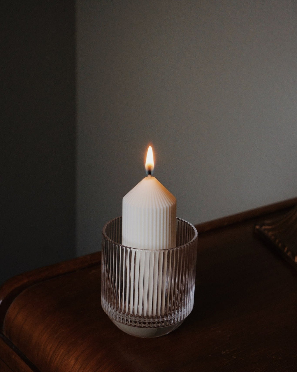 Lead-free crystal glassware with refill candle lit inside on wooden surface