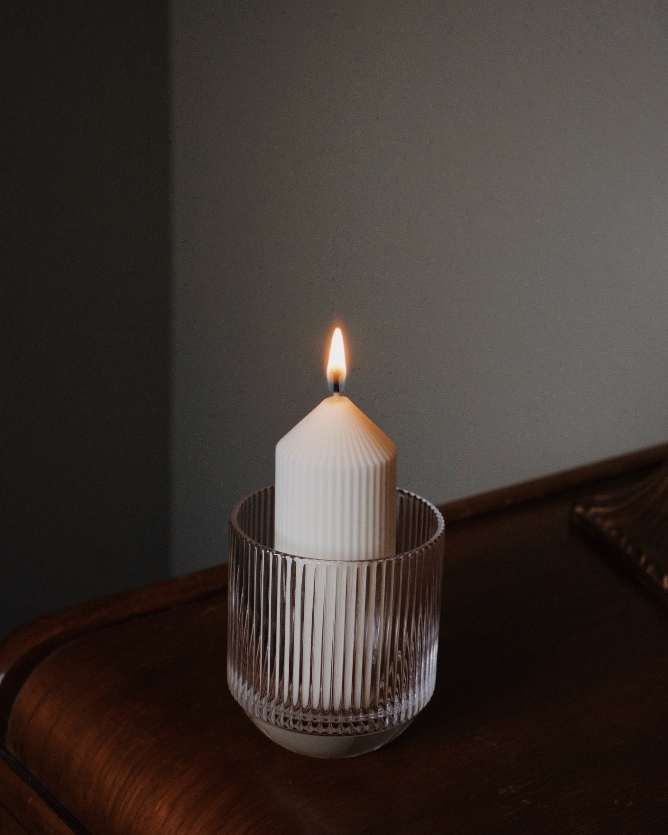 Lead-free crystal glassware with refill candle lit inside on wooden surface