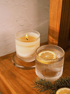 close up of 2 glasses on a bartop, one is a candle, the other is a beverage with a lemon slice