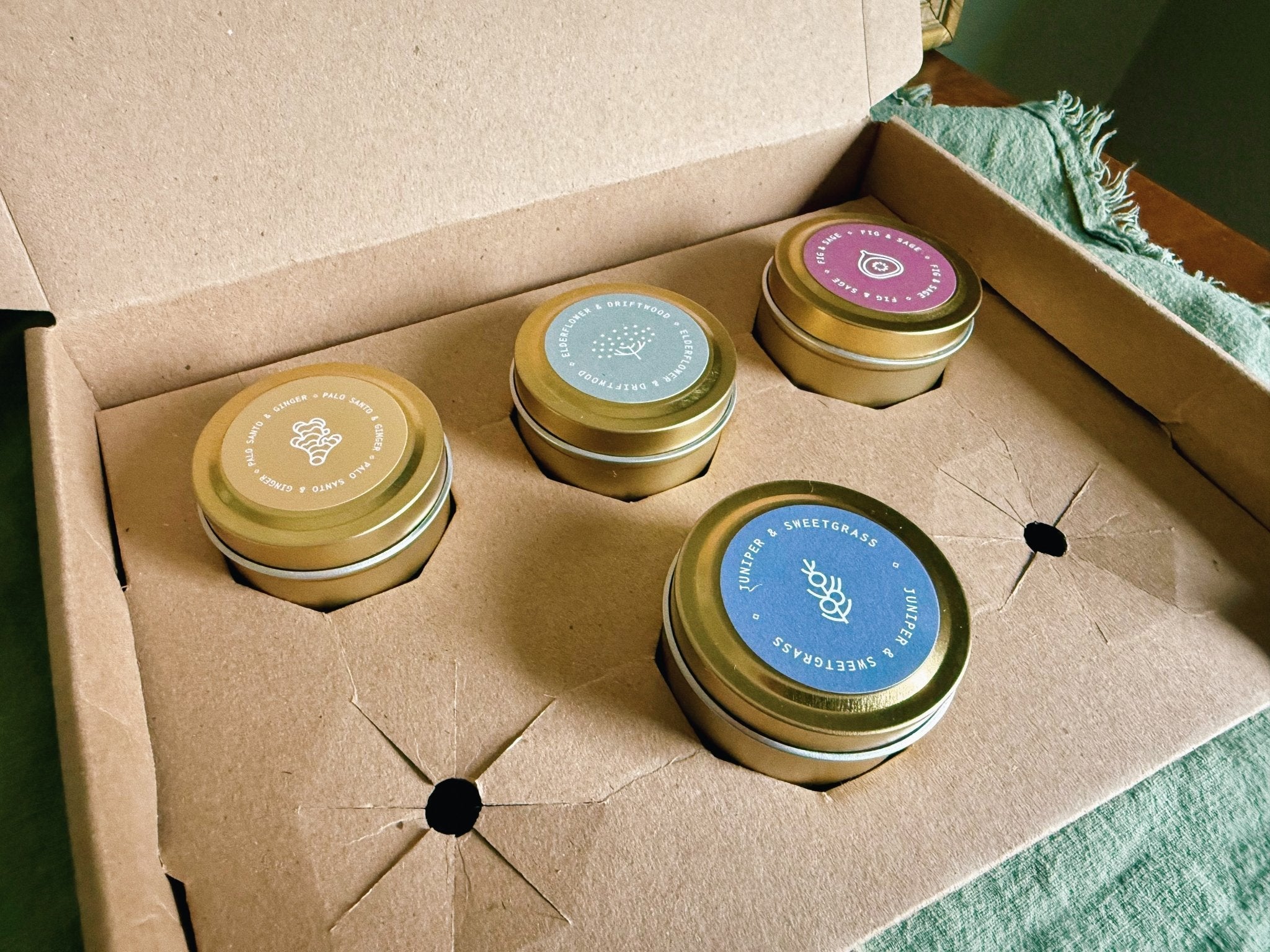 Set of four small cylindrical containers with colorful labels in a cardboard box.