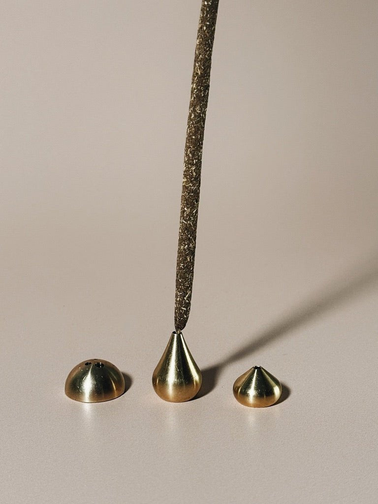 Incense placed inside tall waterdrop holder alongside 2 other brass holders
