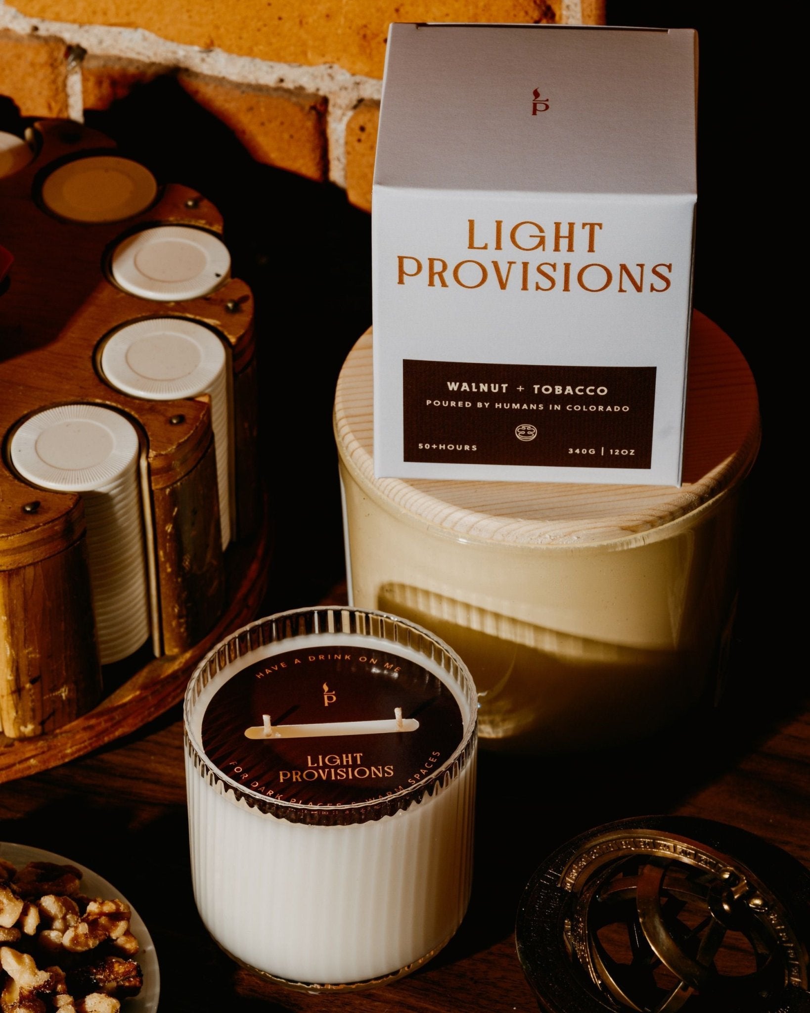 Light Provisions Tobacco Walnut candle and packaging on a wooden surface with a rustic background
