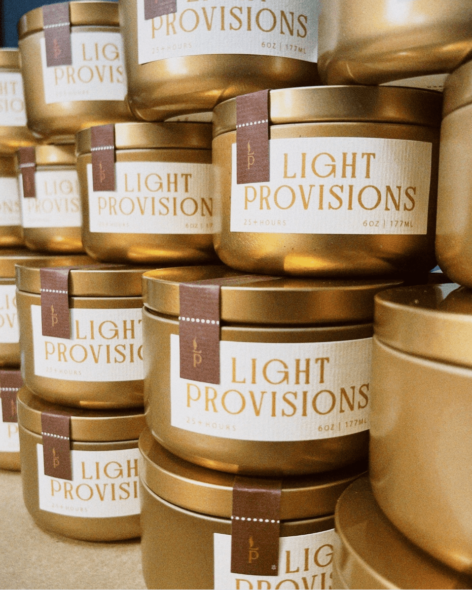 stack of Tobacco Walnut candles in gold travel tins with textured label
