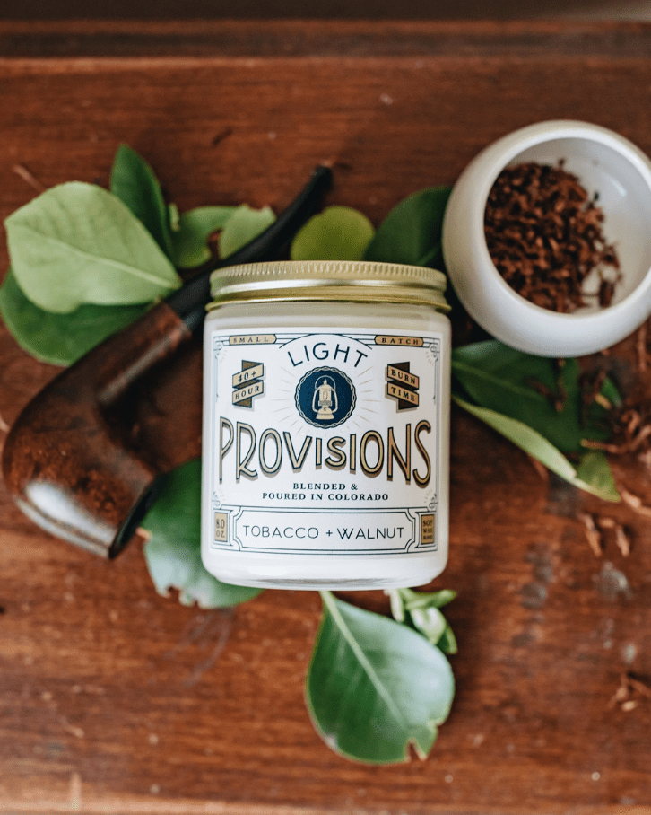 Jar of Tobacco Walnut candle on wooden surface with leaves and a tobacco pipe