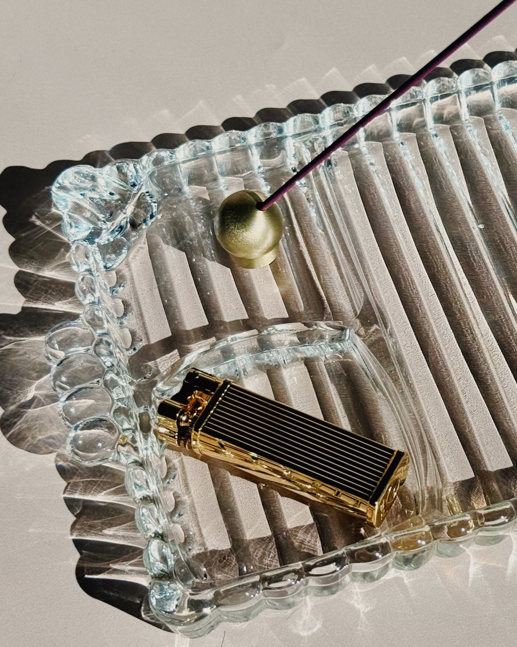 Tsubota Pearl Bolbo lighter photographed outdoors on textured glass, shown in use as a lifestyle shot.