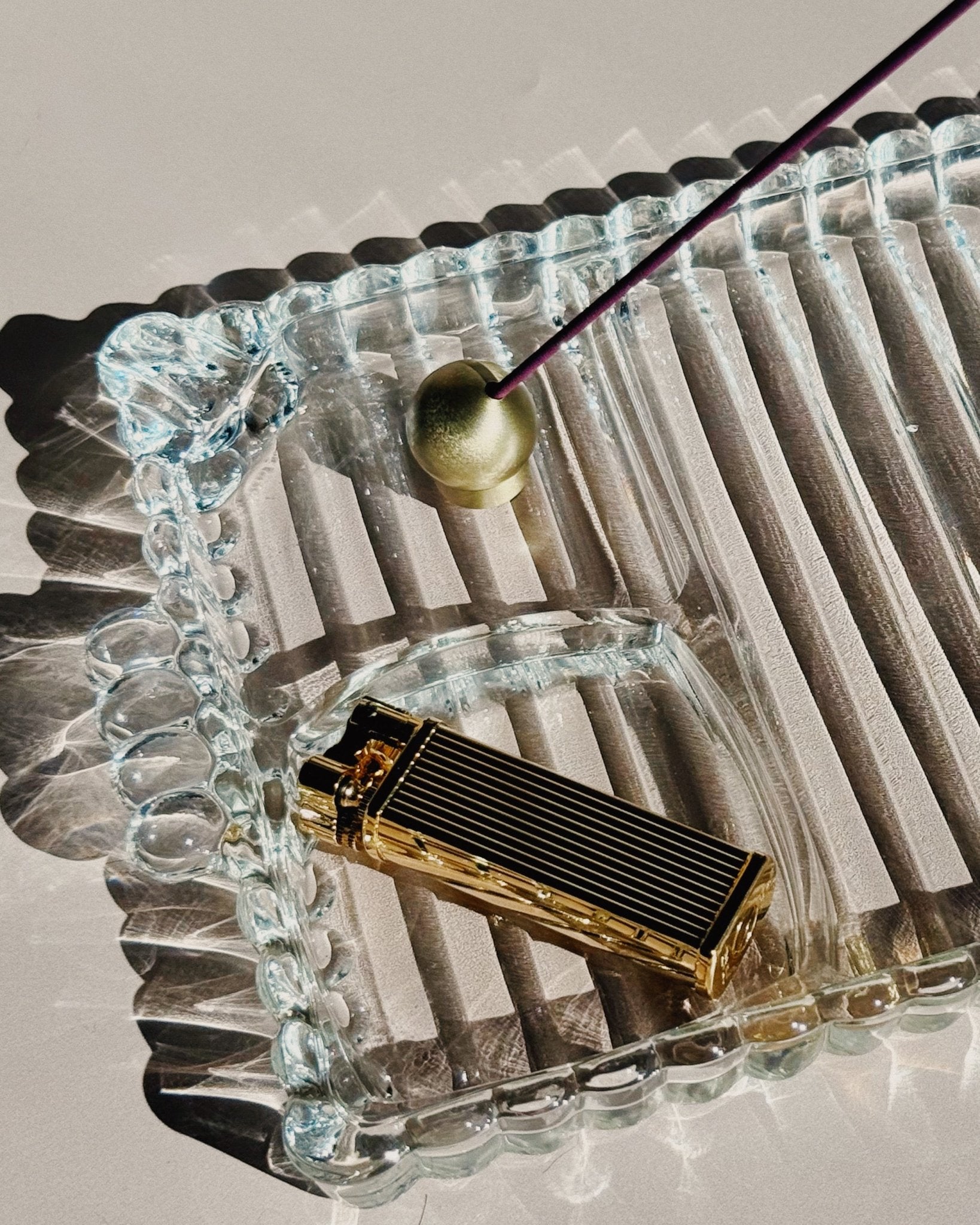 Tsubota Pearl Bolbo lighter photographed outdoors on textured glass, shown in use as a lifestyle shot.