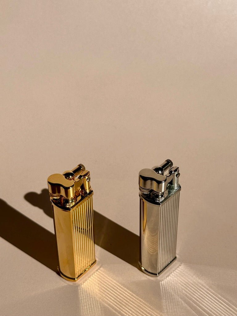 Brass and chrome Tsubota Pearl Bolbo lighters standing upright, photographed together on a neutral surface.