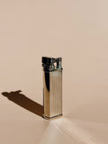 Striped Silver Tsubota Pearl Bolbo lighter standing upright, photographed with soft shadow on a neutral backdrop.