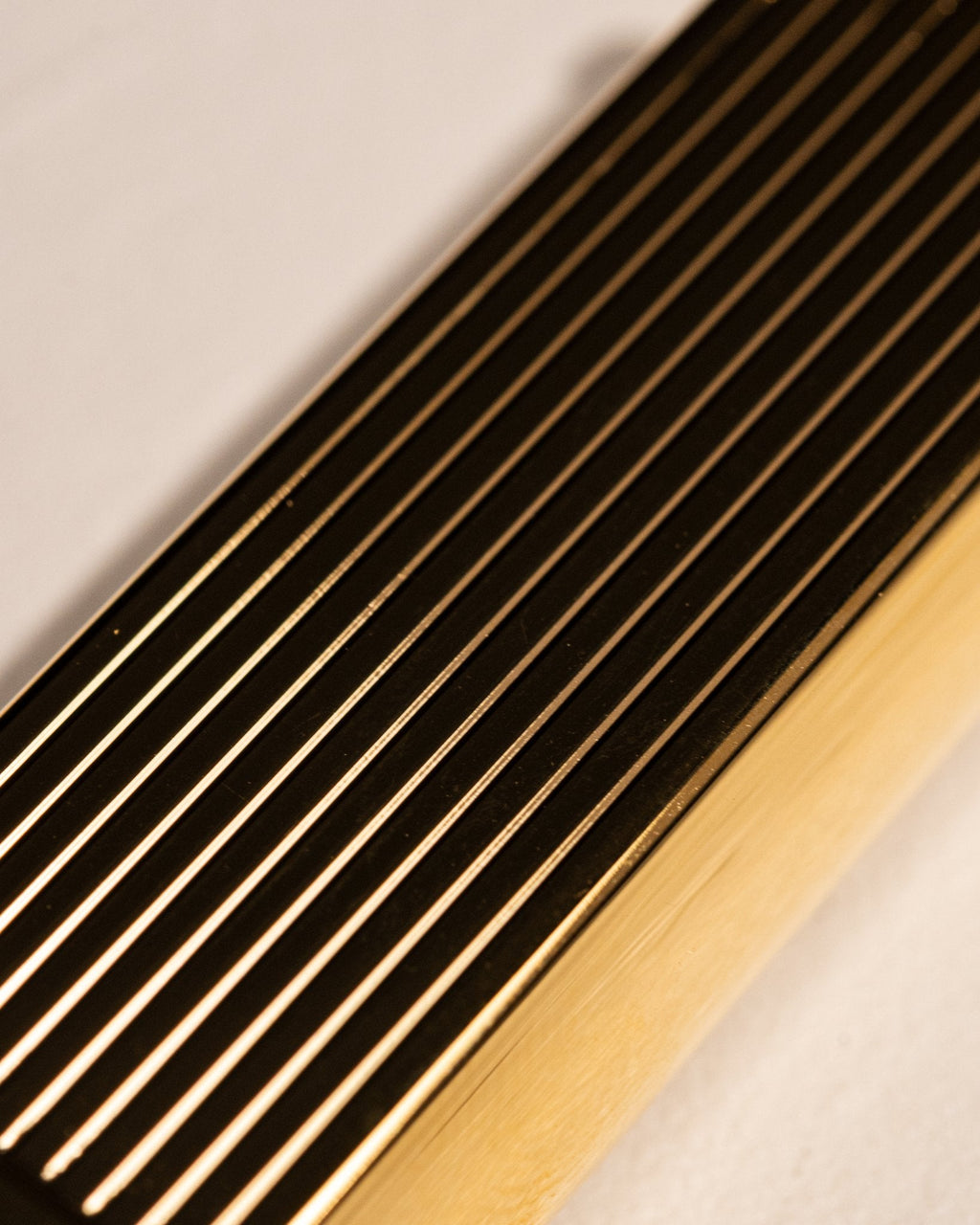 Detailed view of gold Bolbo Striped lighter with finely machined fluted finish
