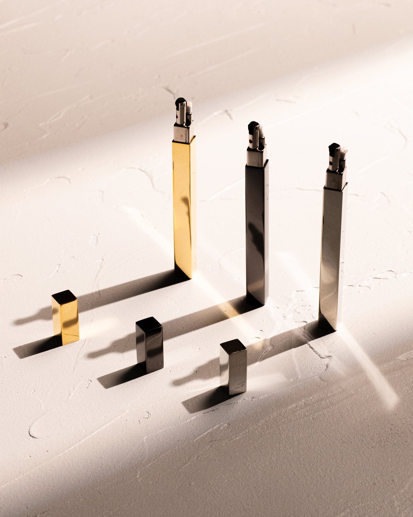 Tsubota Pearl Queue stick lighters in gold, silver, and black with caps removed