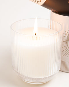 Tobacco & Walnut ribbed glass tumbler candle lit, warm glow reflecting in textured glass on white background.