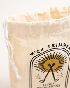Close-up of Light Provisions cotton storage bag with wick trimmer peeking out from the drawstring opening.