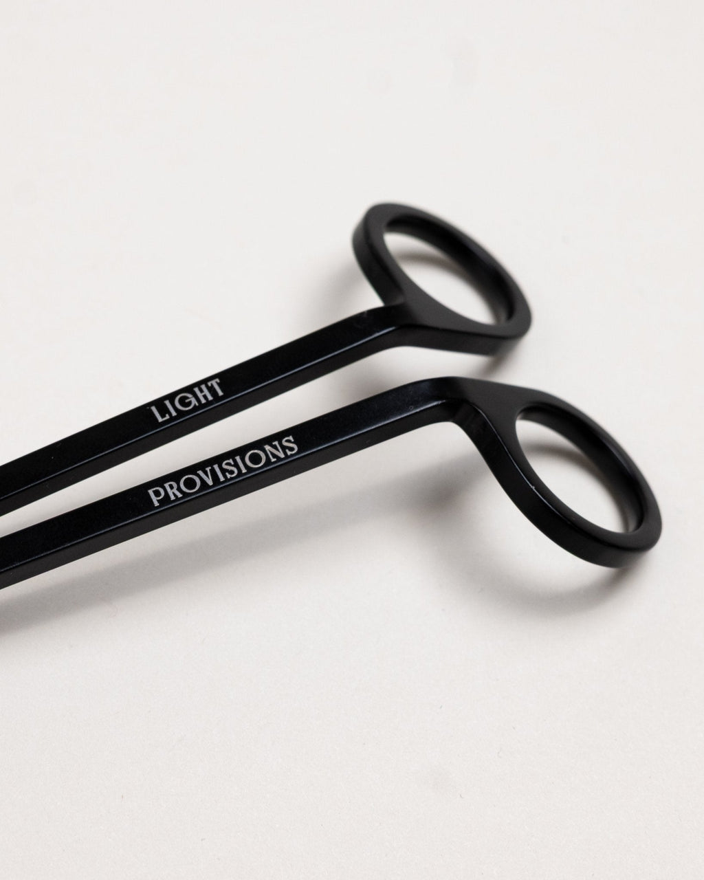 Close-up of black wick trimmer handles engraved with “Light Provisions” branding.