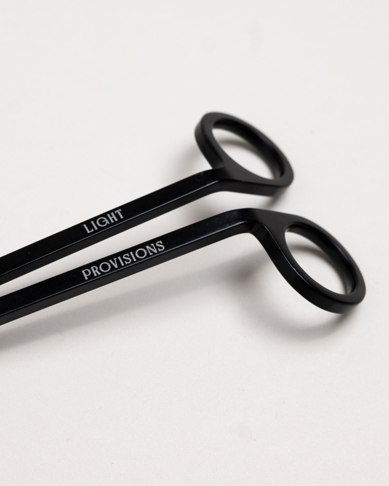 Close-up of black wick trimmer handles engraved with “Light Provisions” branding.