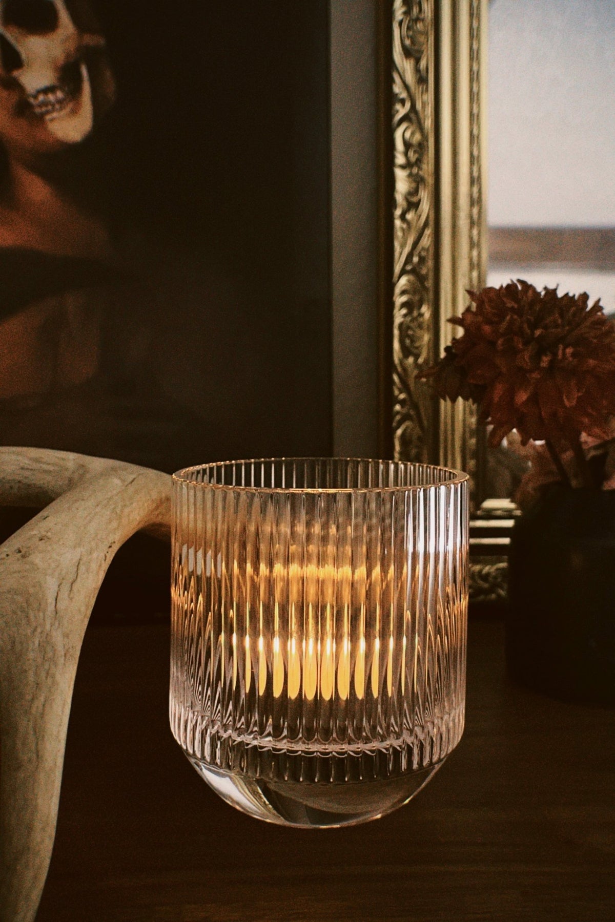 LP signature glass tumbler used to burn a 2 oz sample candle, with a decorative frame and skull in the background.