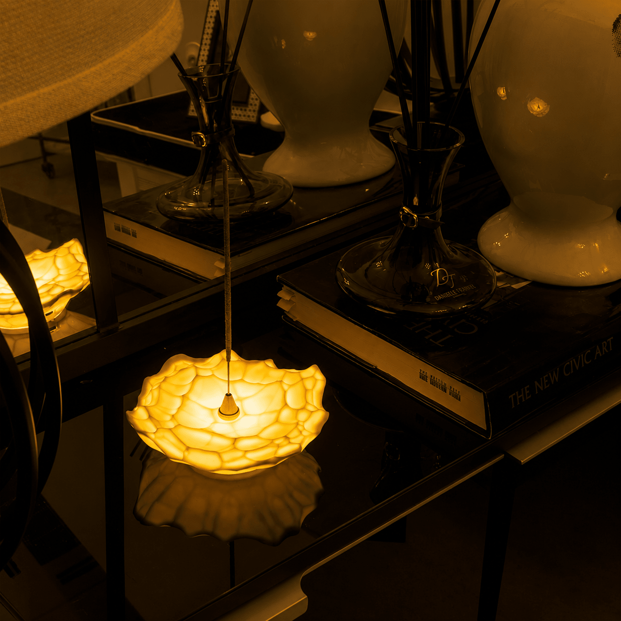 Gem sculptural incense holder light illuminated on a side table among books and decorative objects