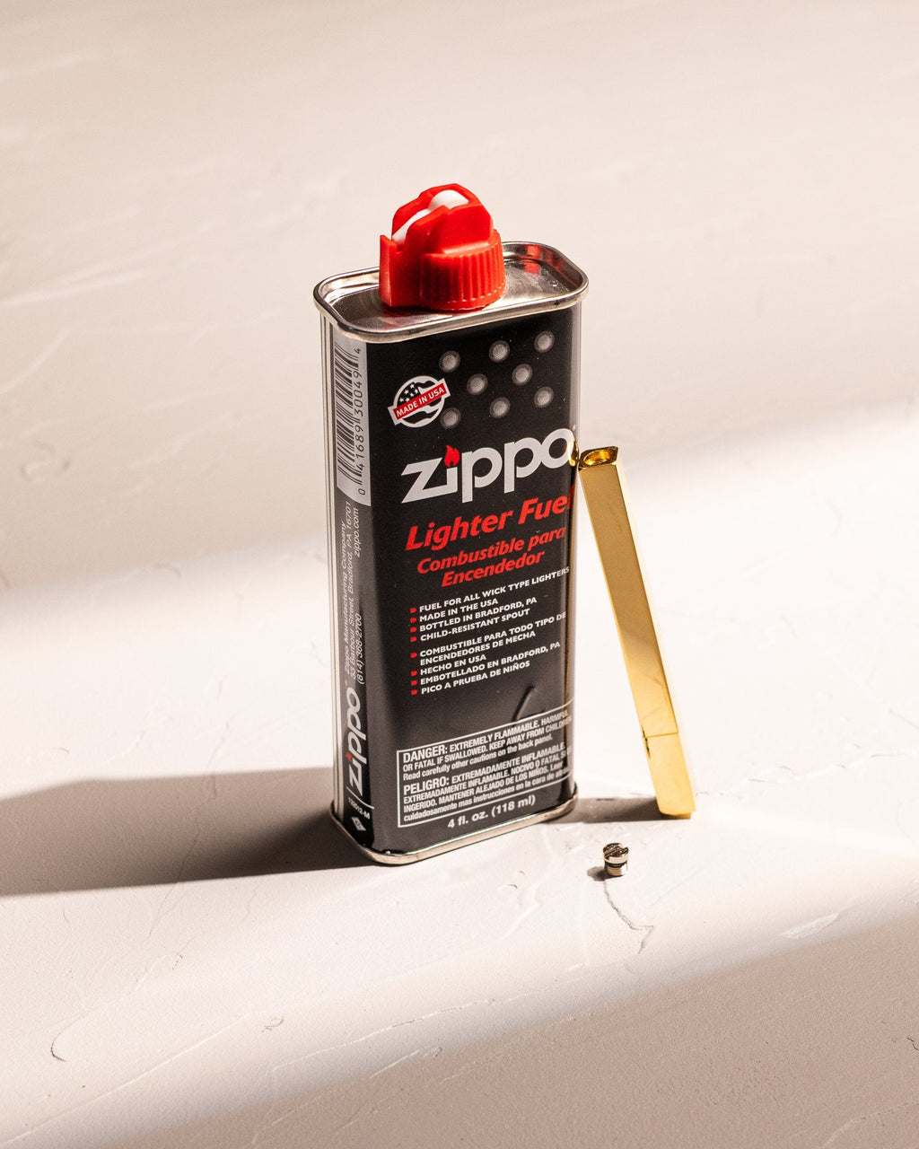 Zippo lighter fluid can with a red cap and a Tsubota Pearl Queue stick lighter on a white background