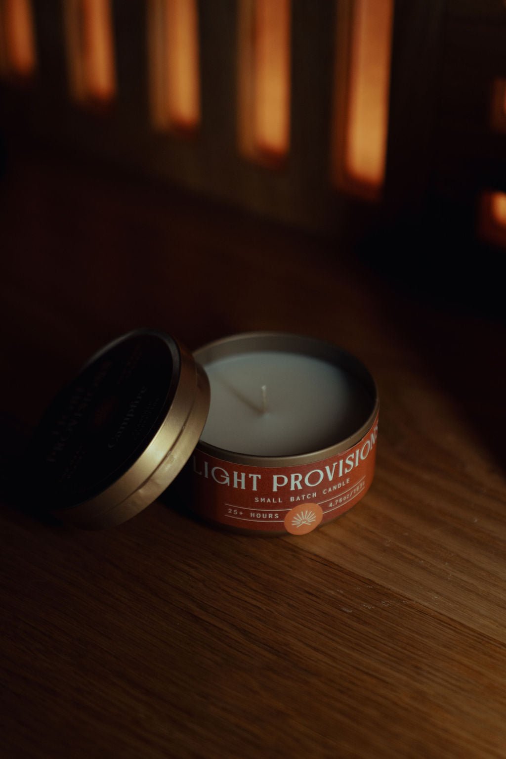 Campfire Candle travel tin with lid removed showing wax on wood surface