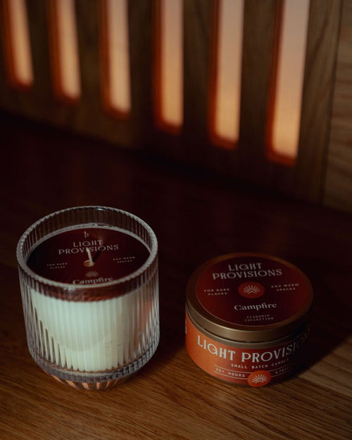  Light Provisions Campfire candle set with ribbed glass tumbler and gold travel tin, placed on wood with warm lighting.