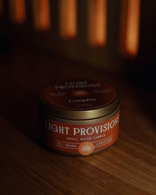 Campfire Candle 4.75 oz travel tin with brown label styled on wood surface