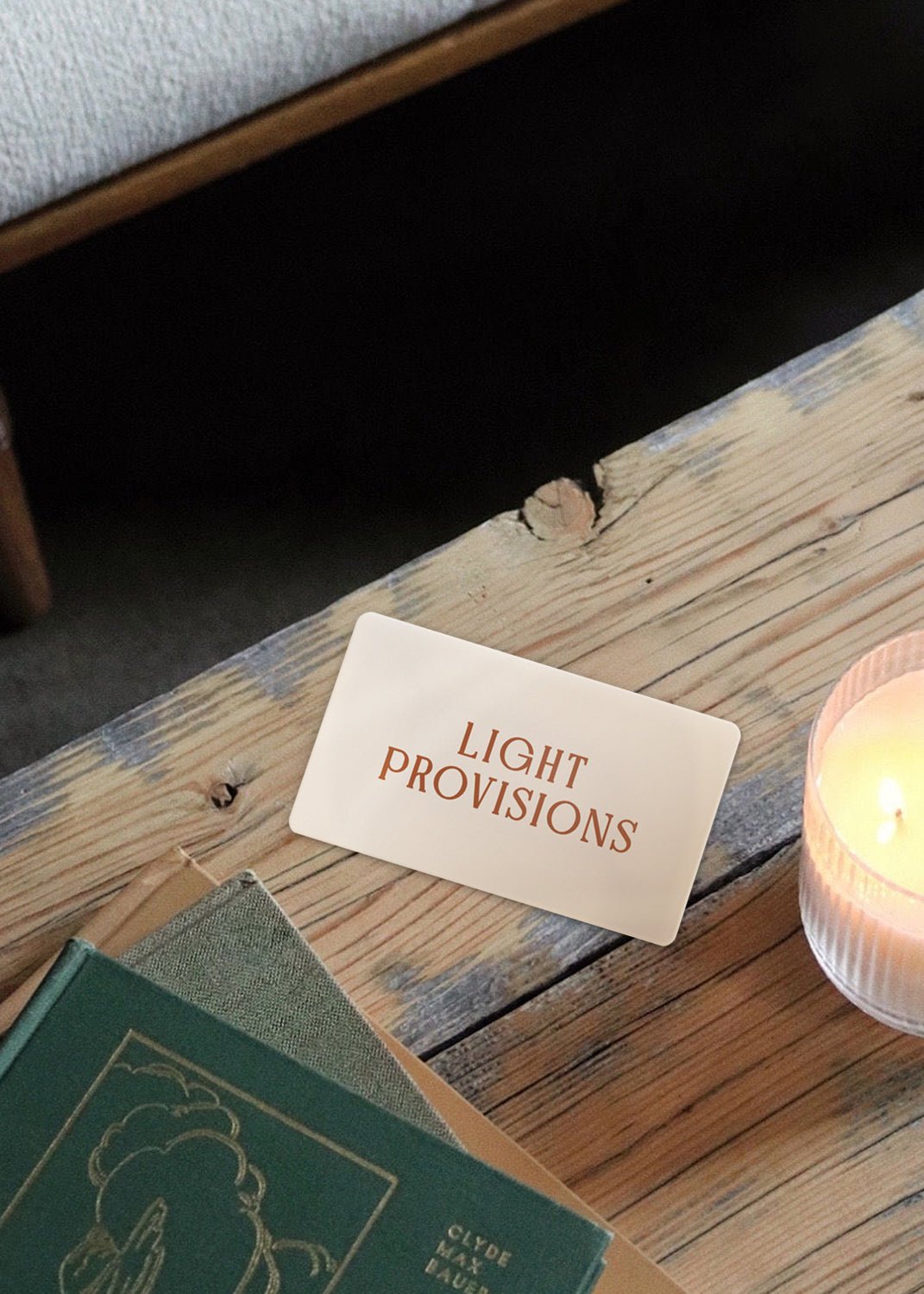 Light Provisions gift card on wooden rustic surface next to lit candle in signature ribbed tumbler