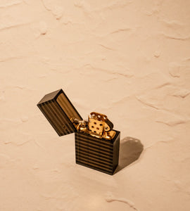 Black-striped Tsubota Pearl Hard Edge lighter with lid open, gold flint mechanism visible on marble surface