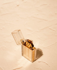 Angled top-down view of transparent striped Tsubota Pearl lighter with exposed gold ignition system

