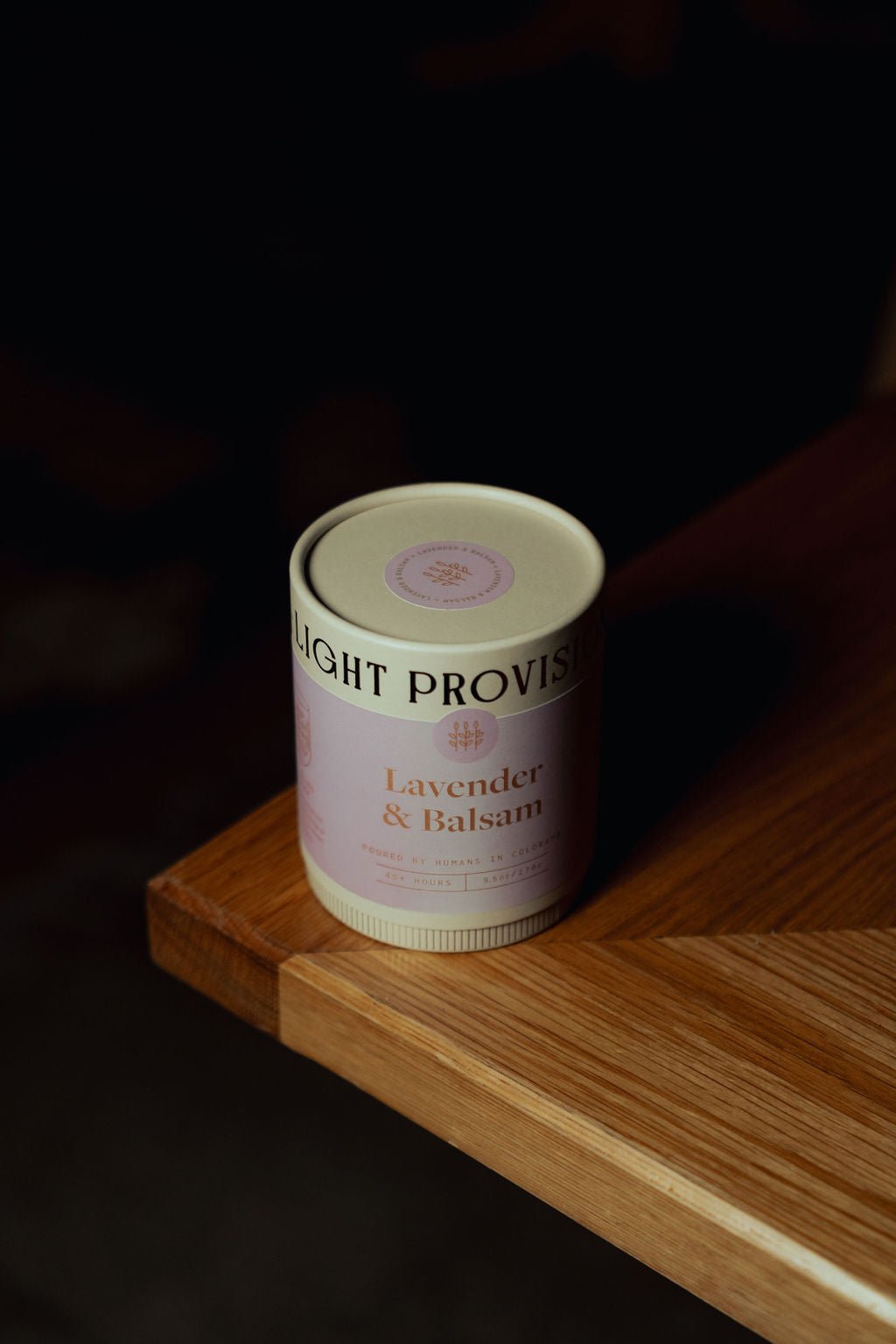Lavender Balsam candle in 9.5 oz ribbed glass tumbler with purple label on wooden surface